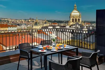 a table on a balcony with a view of a city at DownTown Suites Rubesova in Prague