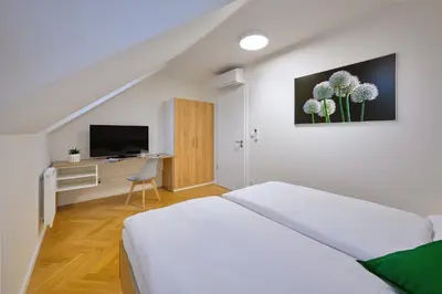 a bedroom with a bed and a desk with a tv at DownTown Suites Rubesova in Prague