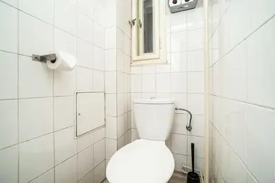 a bathroom with a toilet with a mirror and a window at Apartment in Zizkov -202- in Prague