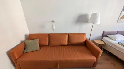 an orange couch in a room with a bed at Apartment in Zizkov -202- in Prague