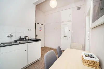 a kitchen with white cabinets and a table with chairs at Apartment in Zizkov -203- in Prague