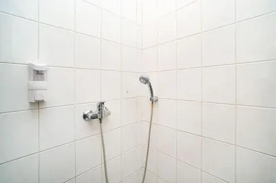 a shower with a hose in a white tiled bathroom at Apartment in Zizkov -203- in Prague