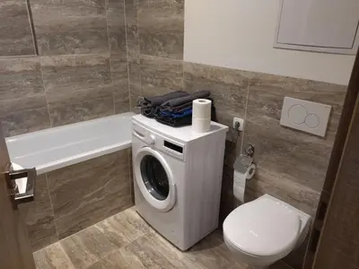 a bathroom with a washing machine and a toilet at Brand new two room apartment #34 with free secure parking in the center in Prague