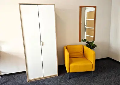 a yellow chair in a room with a mirror at Flat in Zizkov -303- in Prague