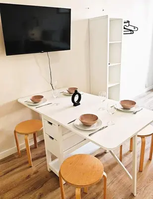 a white table with chairs and a tv on a wall at Flat in Zizkov -303- in Prague