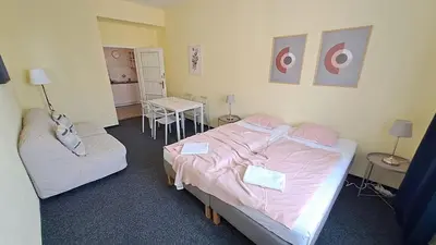 a bedroom with two beds with pink sheets and a table at Flat in Zizkov -402- in Prague