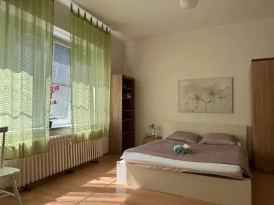 a bedroom with a bed and a window with green curtains at Rooms in the Center of Old Town in Prague