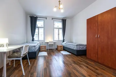 a bedroom with two beds and a desk and a table at Apartments Kamenicka 23 in Prague