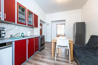 a kitchen with red cabinets and a small table with a chair at Apartments Kamenicka 23 in Prague