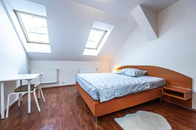 a bedroom with a bed and a desk and windows at Apartments Kamenicka 23 in Prague