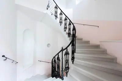 a white staircase with black railings in a house at Spacious apartment with balcony at Wenceslas Sq in Prague