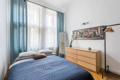 a bedroom with a blue bed and a dresser and a window at Spacious apartment with balcony at Wenceslas Sq in Prague