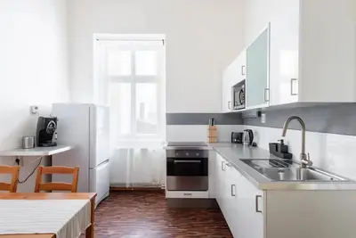 a kitchen with white appliances and a wooden floor at Spacious apartment with balcony at Wenceslas Sq in Prague