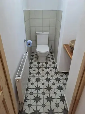 a bathroom with a toilet and a black and white tile floor at Chalupa Zátyní - celý objekt in Dubá