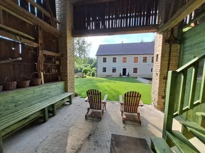 two chairs and a bench on a porch with a building at Chalupa Zátyní - celý objekt in Dubá