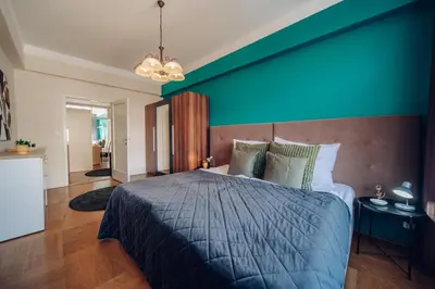 a bedroom with a large bed with a blue wall at Downtown 2BD riverside apartment near dancing house in Prague