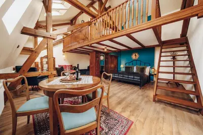 a living room with a staircase and a table and chairs at Magnificent historical penthouse in the heart of Prague in Prague