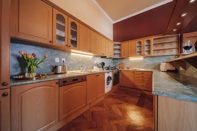 a kitchen with wooden cabinets and a washer and dryer at Magnificent historical penthouse in the heart of Prague in Prague