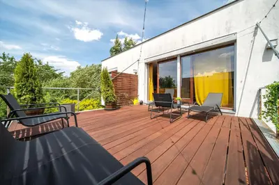 a wooden deck with chairs and tables on a building at Marvel 2BD Apartment in modern villa with cozy terrace in Prague