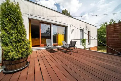 a wooden deck with two chairs and a tree at Marvel 2BD Apartment in modern villa with cozy terrace in Prague