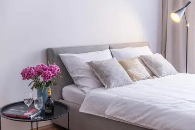 a white bed with a table with flowers and wine glasses at New design APT - central location Wenceslas Square in Prague