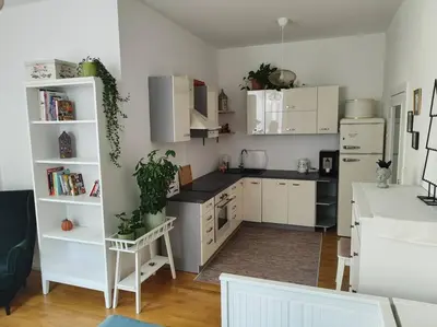 a kitchen with white cabinets and black counter tops at Studio with balcony in Vinohrady in Prague
