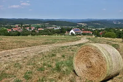 a stack of hay in a field with a town in the background at Pension Jezerná in Zduchovice