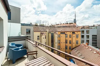 a balcony with a blue chair and some buildings at Cosy studio with terrace by tram in Prague