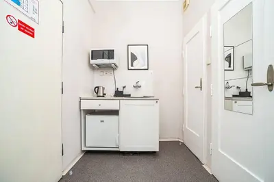 a small white kitchen with a desk and a tv at Cosy studio with terrace by tram in Prague