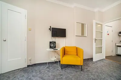 a room with a yellow chair and a table and a tv at Cosy studio with terrace by tram in Prague