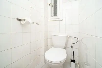 a white bathroom with a toilet and a window at Cosy studio with terrace by tram in Prague