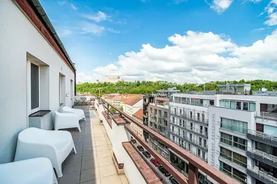 a balcony with white chairs on a building at 3 bedroom flat with amazing terrace in Prague