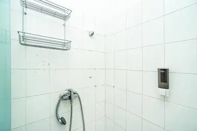 a white tiled bathroom with a shower head at 3 bedroom flat with amazing terrace in Prague