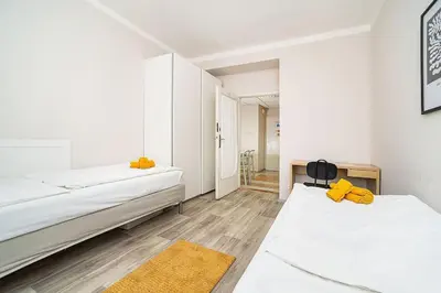 two beds in a room with white walls and wooden floors at 3 bedroom flat with amazing terrace in Prague