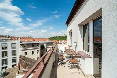 a balcony with chairs and tables on a building at Bright 2 bed with big terrace by tram in Prague