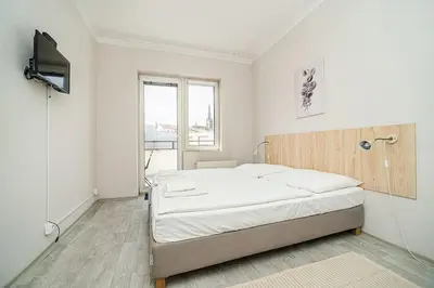 a white bedroom with a bed and a television at Bright 2 bed with big terrace by tram in Prague