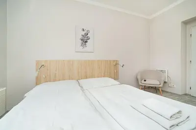 a white bed in a white bedroom with a chair at Bright 2 bed with big terrace by tram in Prague