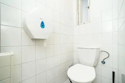 a white bathroom with a toilet and a window at Bright 2 bed with big terrace by tram in Prague