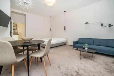 a living room with a blue couch and a table at Modern studio with balcony + TV in Prague