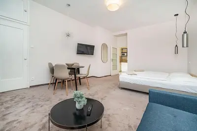 a living room with a couch and a table and a bed at Modern studio with balcony + TV in Prague