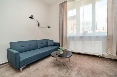 a living room with a blue couch and a table at Modern studio with balcony + TV in Prague