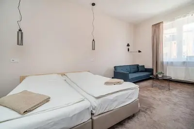 a bedroom with two beds and a blue couch at Modern studio with balcony + TV in Prague