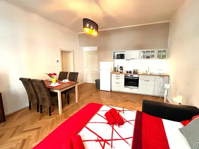 a living room with a dining room table and a kitchen at Cute Apartment Zborovska in Prague