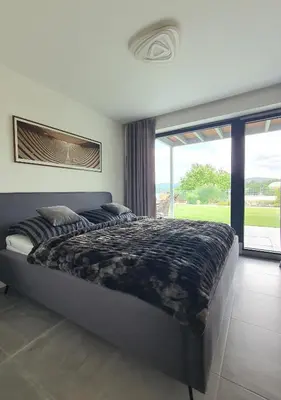 a bedroom with a large bed and a large window at Pláž Hrdlička in Buš