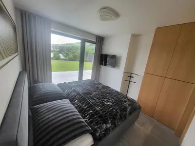 a bedroom with a bed and a large window at Pláž Hrdlička in Buš