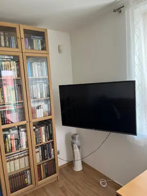a flat screen tv hanging on a wall next to book shelves at Apartmán s wellness službami in Čerčany