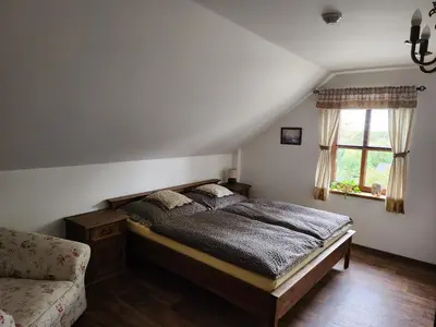 a bedroom with a bed and a chair and a window at Hospůdka Na Trucovně in Sázava