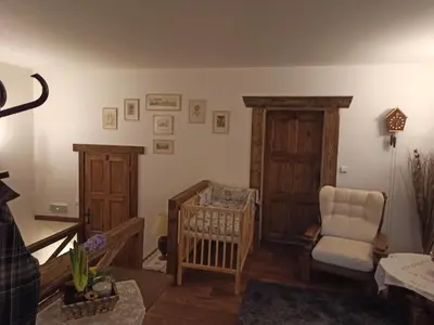 a living room with a crib and a chair at Hospůdka Na Trucovně in Sázava