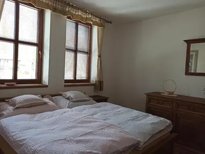 a bedroom with a large bed and two windows at Hospůdka Na Trucovně in Sázava