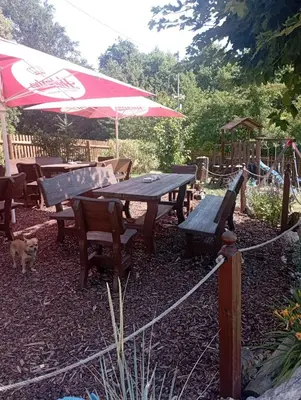 a picnic table and benches with an umbrella and a dog at Hospůdka Na Trucovně in Sázava